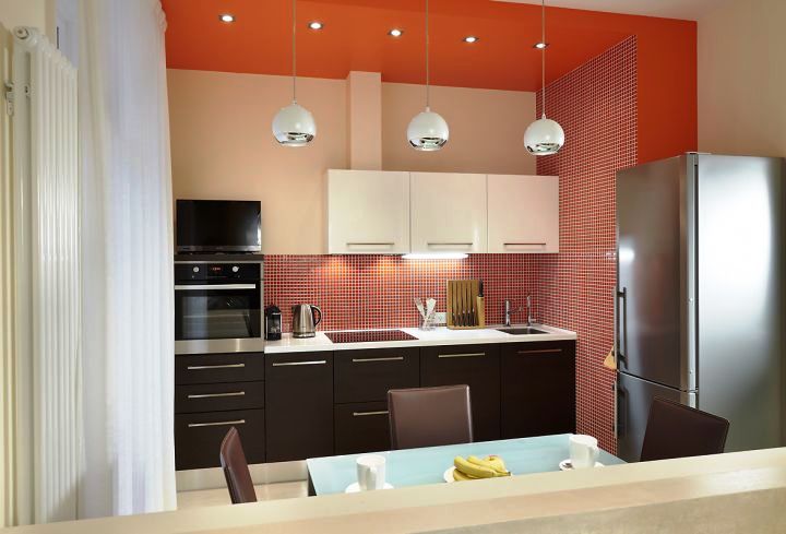 Контраст оранжевой стены с черно-белой кухней